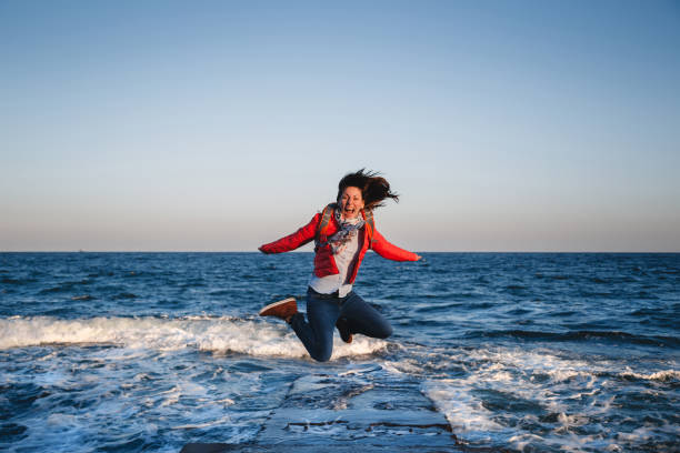 istock Young happy girl with backpack jumping on a seaside at sunset 659509576