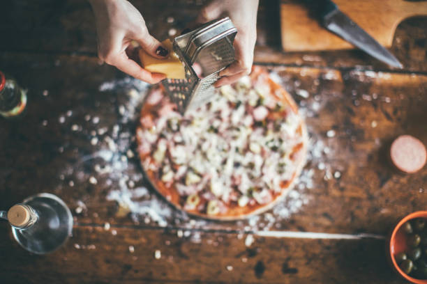 women hand grating the cheese on the pizza - recipe ingredient grater cheese grater imagens e fotografias de stock