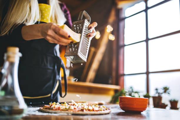 le donne grattugiano a mano il formaggio sulla pizza - baking flour ingredient animal egg foto e immagini stock