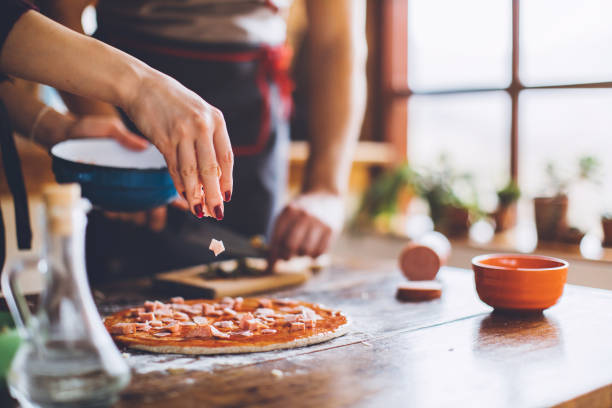 giovane coppia che fa pizza fresca in cucina - tomato sauce domestic kitchen meat cheese foto e immagini stock