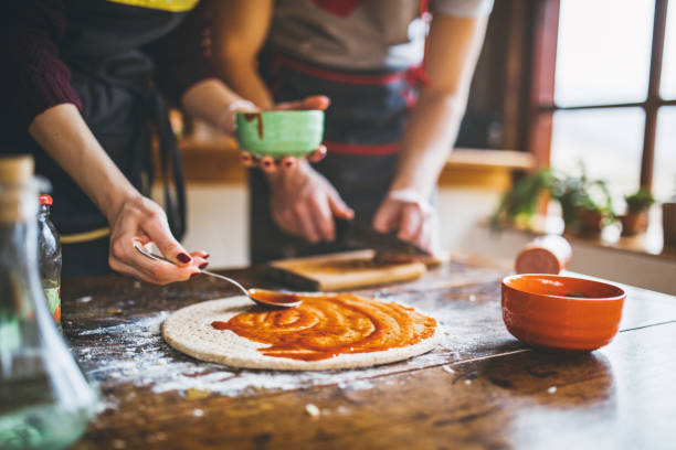 giovane coppia che fa pizza fresca in cucina - baking flour ingredient animal egg foto e immagini stock