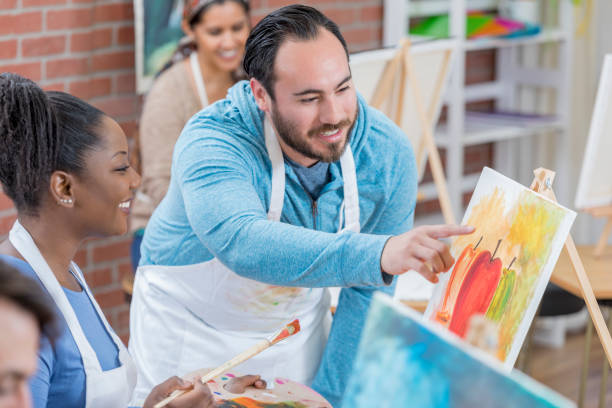 istock Hispanic art studio owner teaches painting lessons 659542618