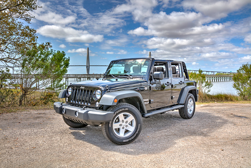 Mt Pleasant, South Carolina, USA - March 26, 2017: This is a picture of the Jeep Wrangler Unlimited and is an example of used 2015 model. Shot outdoors in the morning at Remley's Point in Mt Pleasant, SC. The Cooper River Bridge is seen in the background.