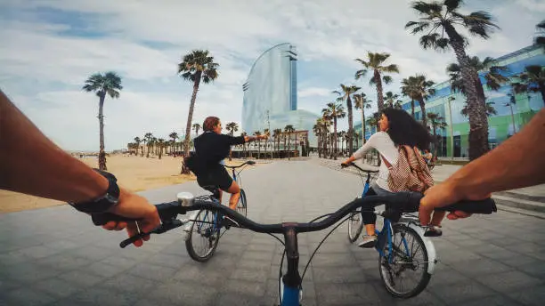POV bicycle riding with friends at Barceloneta beach in Barcelona, Spain