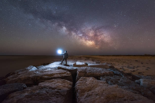 istock Man lighting up a jetty under the milky way galaxy 659579658