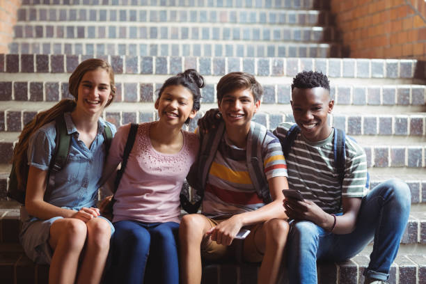 istock Portrait of happy classmates sitting on staircase 659580202
