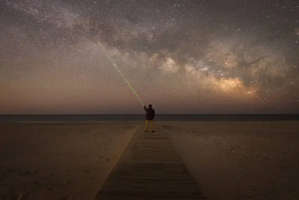 Photo of Man pointing a laser at the stars