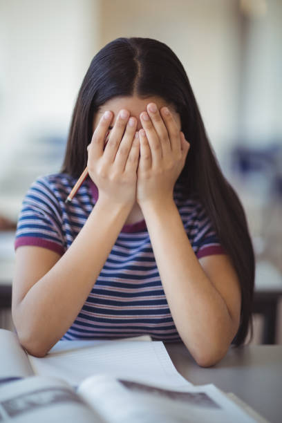 istock Stressed schoolgirl doing covering her face in classroom 659610608