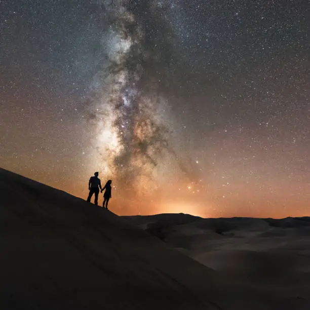 Photo of A couple holds hands under the Milky Way Galaxy