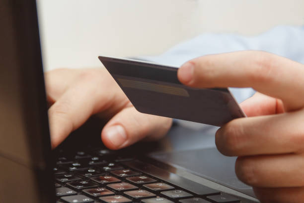 Close Up Of A Man Shopping Online Using Laptop With Credit Card stock photo