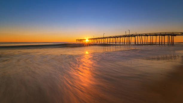 Long exposure of water with Nags Head in the back Sunrise from Nags Head Pier in North Carolina. bodie island stock pictures, royalty-free photos & images