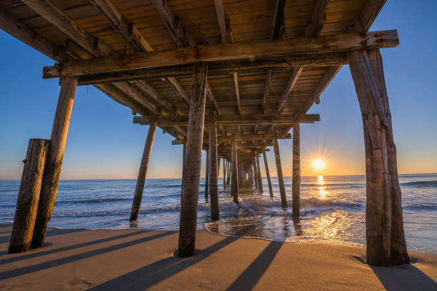 Underneath Nags Head Pier at sunrise Sunrise from Nags Head Pier in North Carolina. bodie island stock pictures, royalty-free photos & images