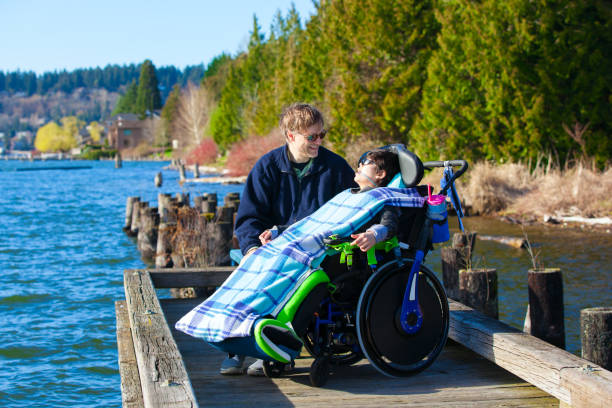 istock Disabled boy in wheelchair talking with father at lakeside park 659830586