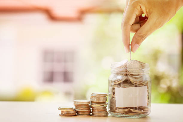 istock Hand putting Coins in glass jar and empty label 659869036