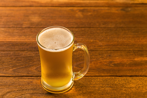 Glass of beer on wooden table in Golden Light.