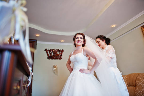 istock Bridesmaids helping dressed bride on wedding day at morning. 659988018