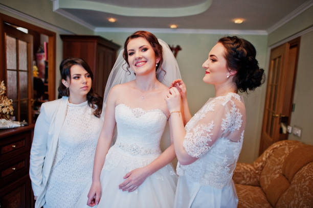 istock Bridesmaids helping dressed bride on wedding day at morning. 659988228