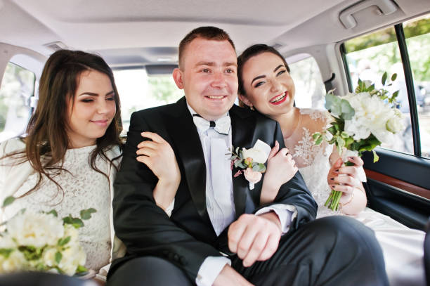 istock Happy smiled groom sitting on wedding car with bridesmaids. 659988616