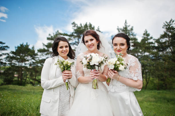 istock Pretty bride with bridesmaids on white dresses with bouquets on hands at wedding day. 659988754