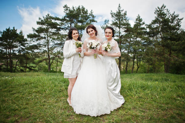 istock Pretty bride with bridesmaids on white dresses with bouquets on hands at wedding day. 659988808