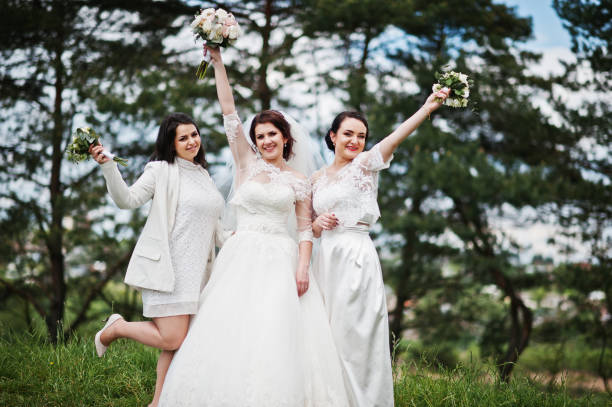 istock Pretty bride with bridesmaids on white dresses with bouquets on hands at wedding day. 659988942