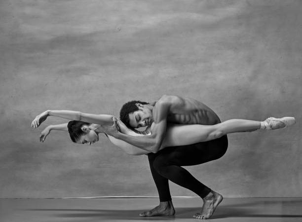 Couple of ballet dancers posing over gray background Couple of ballet dancers posing over gray background. Colorless image acrobatic gymnastics stock pictures, royalty-free photos & images