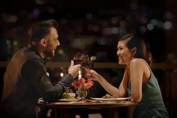 toasting couple - dating restaurant dinner couple imagens e fotografias de stock