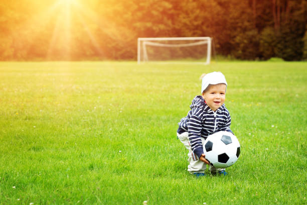 маленький мальчик играет в футбол на поле с воротами - playing field goalie soccer player little boys стоковые фото и изображения