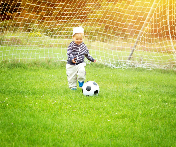 kleine jungen spielen fußball auf dem spielfeld mit toren - playing field goalie soccer player little boys stock-fotos und bilder