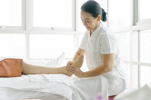 старшая массажистка делает массаж ног - thai ethnicity massaging thailand thai culture стоковые фото и изображения