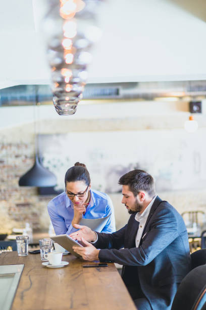istock Handsome, young  businessman, sitting in a bar, drinking coffee, browsing tablet with his associate, young and beautiful business woman 660069842