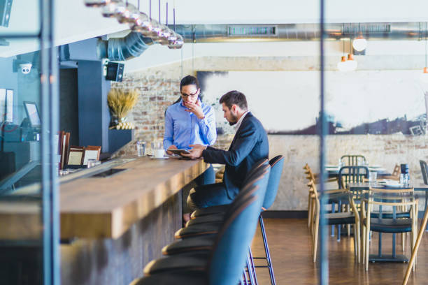 istock Handsome, young  businessman, sitting in a bar, drinking coffee, browsing tablet with his associate, young and beautiful business woman 660070098