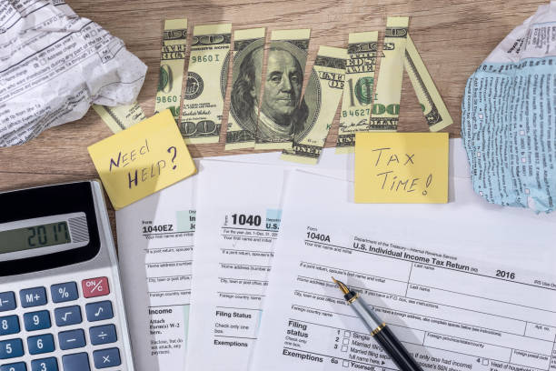 istock torn dollars on tax form, pen and calculator. 660088388