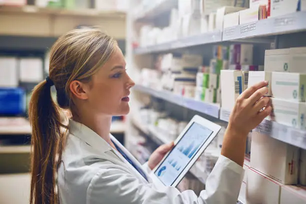 Shot of a pharmacist using her digital tablet while working in a isle