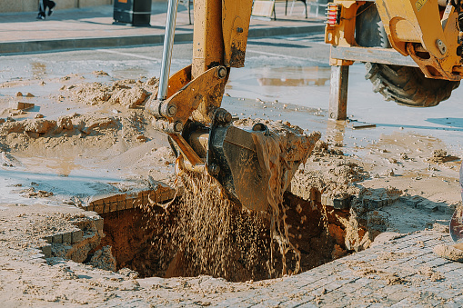 Excavator cleaning mud from area with broken pipeline