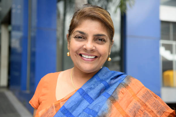 Mature woman in sari outside office building, smiling Sri Lankan woman in her 50s facing camera, wearing traditional clothes and blue scarf, with cheerful expression sri lanka business stock pictures, royalty-free photos & images