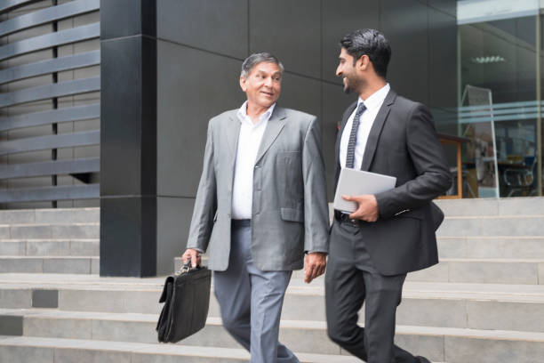 dos hombres de negocios elegante vestidos en pasos fuera de oficina - smartly fotografías e imágenes de stock