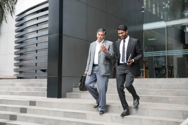 Photo of Senior businessman an young male colleague leaving offices