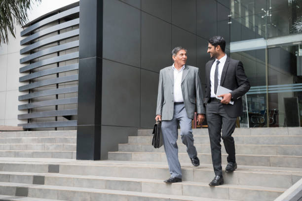 istock Two male business colleagues walking down steps outside office 660151258