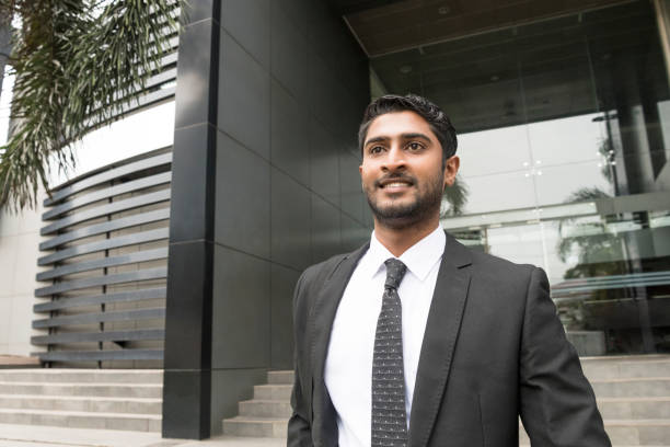 Portrait of confident young businessman with beard in suit Attractive young Sri Lankan office worker outside modern building, looking away sri lanka business stock pictures, royalty-free photos & images