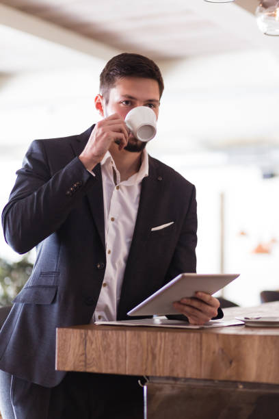 istock Handsome businessman, in a bar, drinking coffee,  browsing tablet, reading news. Some grain added 660151760