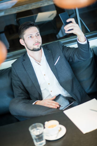 istock Young and handsome businessman, drinking coffee in restaurant, working, browsing digital tablet. Taking selfie. 660152936
