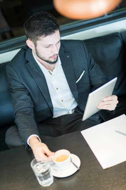 istock Young and handsome businessman, drinking coffee in restaurant, working, browsing digital tablet. 660153034