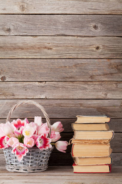 istock Pink tulips bouquet basket and old books 660171482
