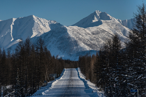 Kolyma track in winter against the background of snow-capped mountains