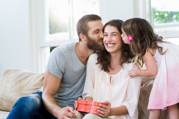 istock Mother receiving a gift from her husband and daughter 660172918