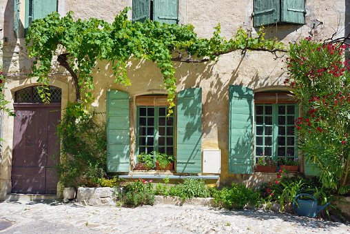 France, Provence - July 16, 2014: Small square in Vaison la Romaine - Place Du Vieux Marche. Typical medieval houses decorated with green plant and flowers in pots.