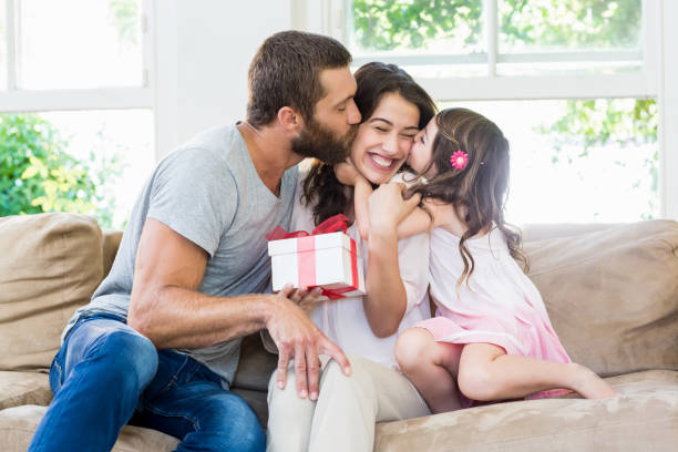 istock Mother receiving a gift from her husband and daughter 660173872
