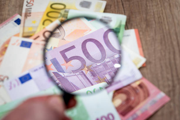 istock different euros banknotes under magnifying glass on desk. 660209940