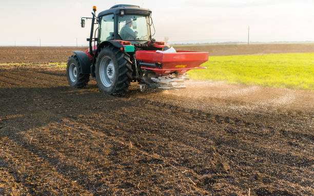 tractor difusión de fertilizantes artificiales en el campo - fertilizante fotos fotografías e imágenes de stock